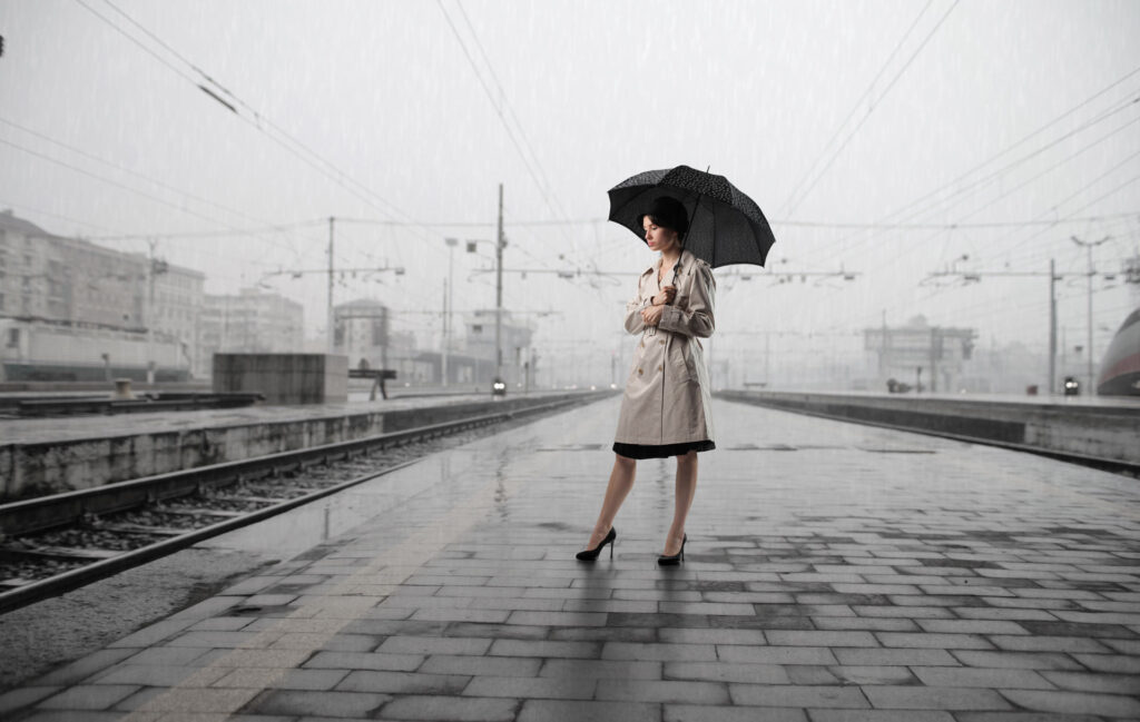 Woman with umbrella standing on the platform of a train station