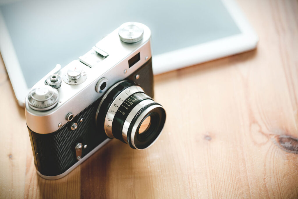 Old vintage camera with a tablet on a wooden table